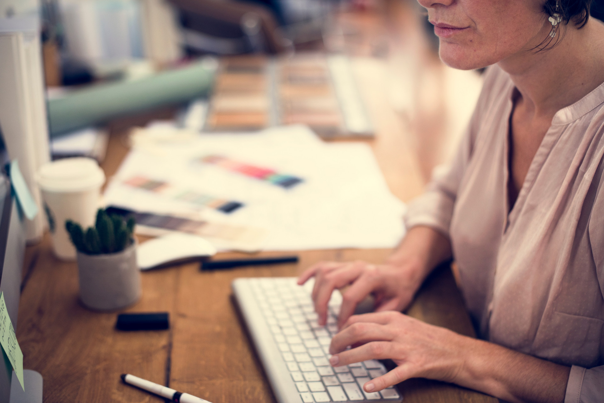 Frau sitzt am Computer und tippt auf der Tastatur.
